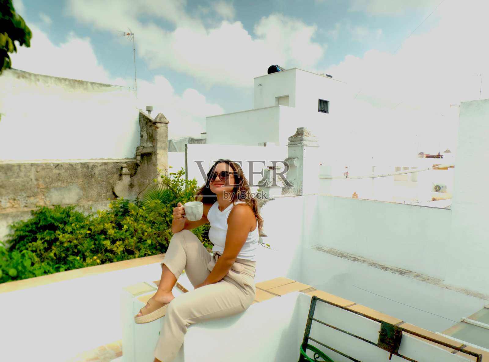 戴着太阳镜的女孩在阳台上喝咖啡照片摄影图片