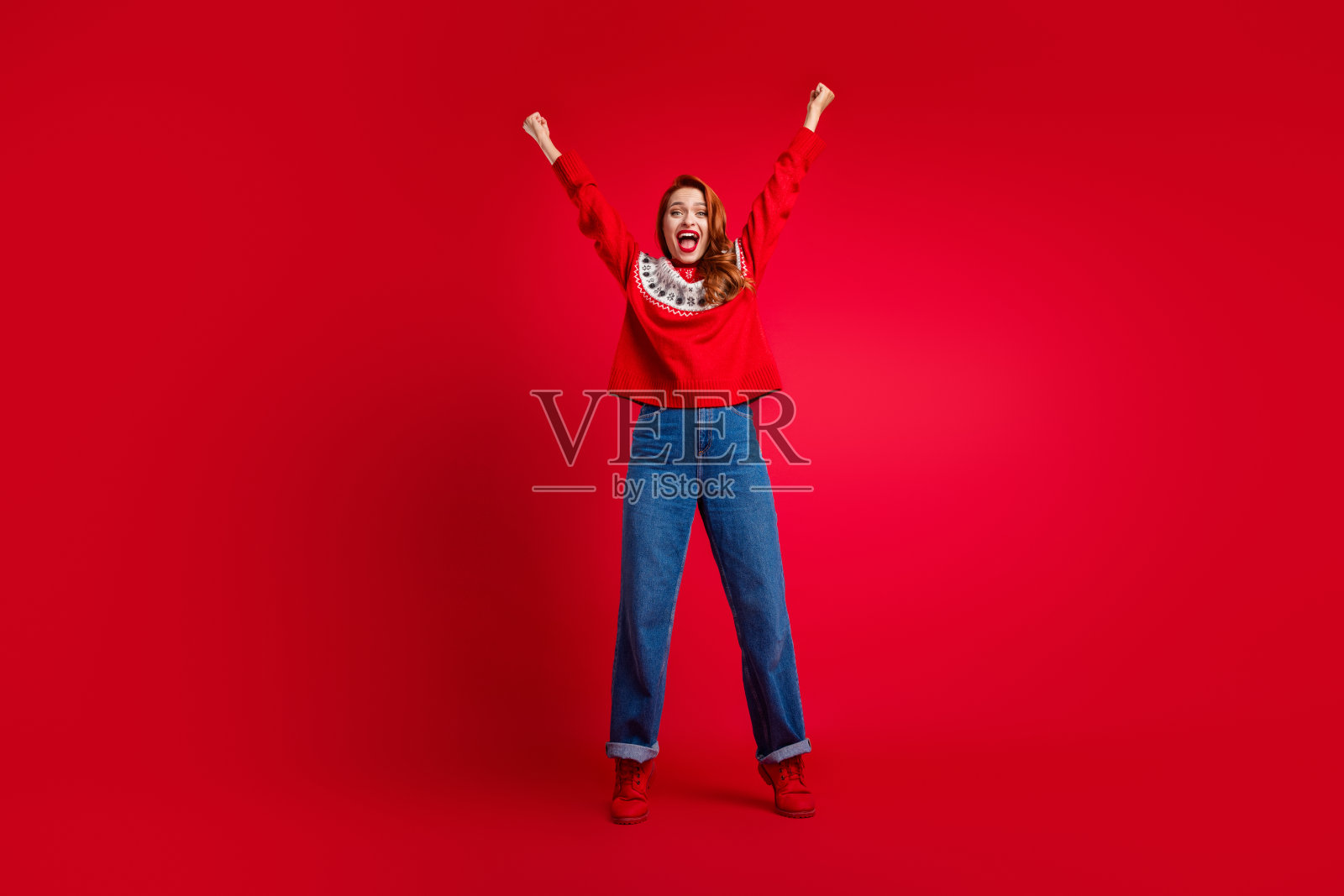 年轻快乐的女孩穿着有趣的毛衣，庆祝圣诞促销，红色背景照片摄影图片