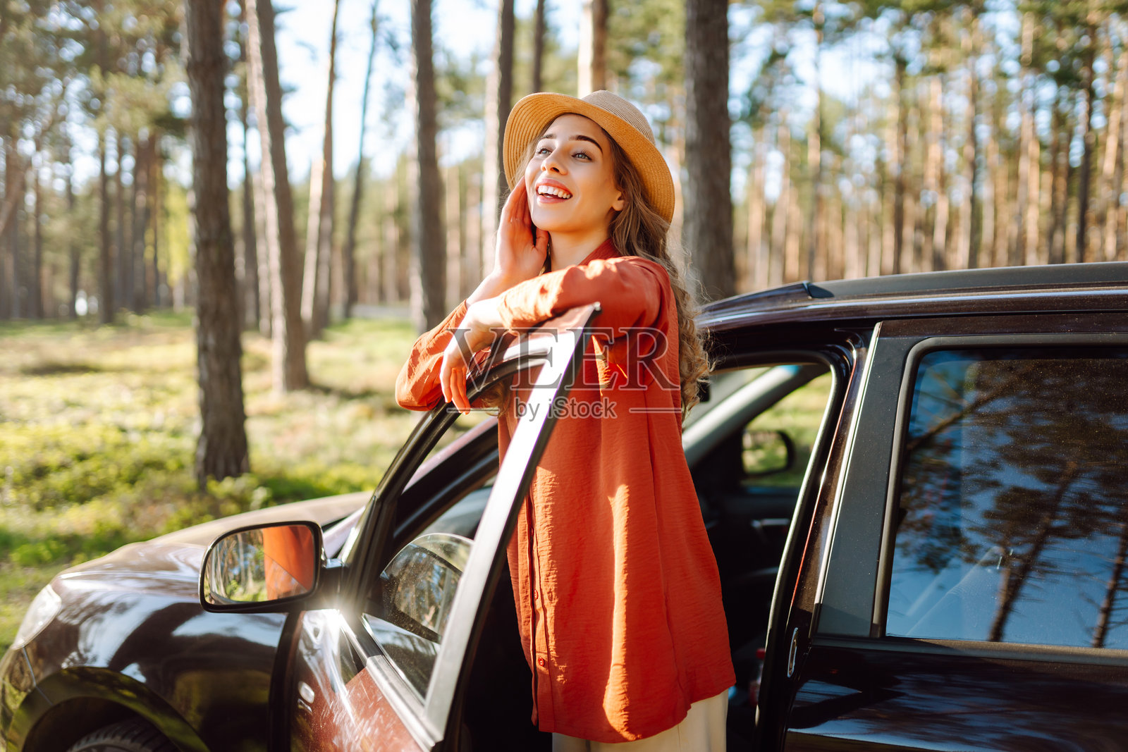 一位女性在森林中她的车旁享受阳光明媚的户外时光。照片摄影图片