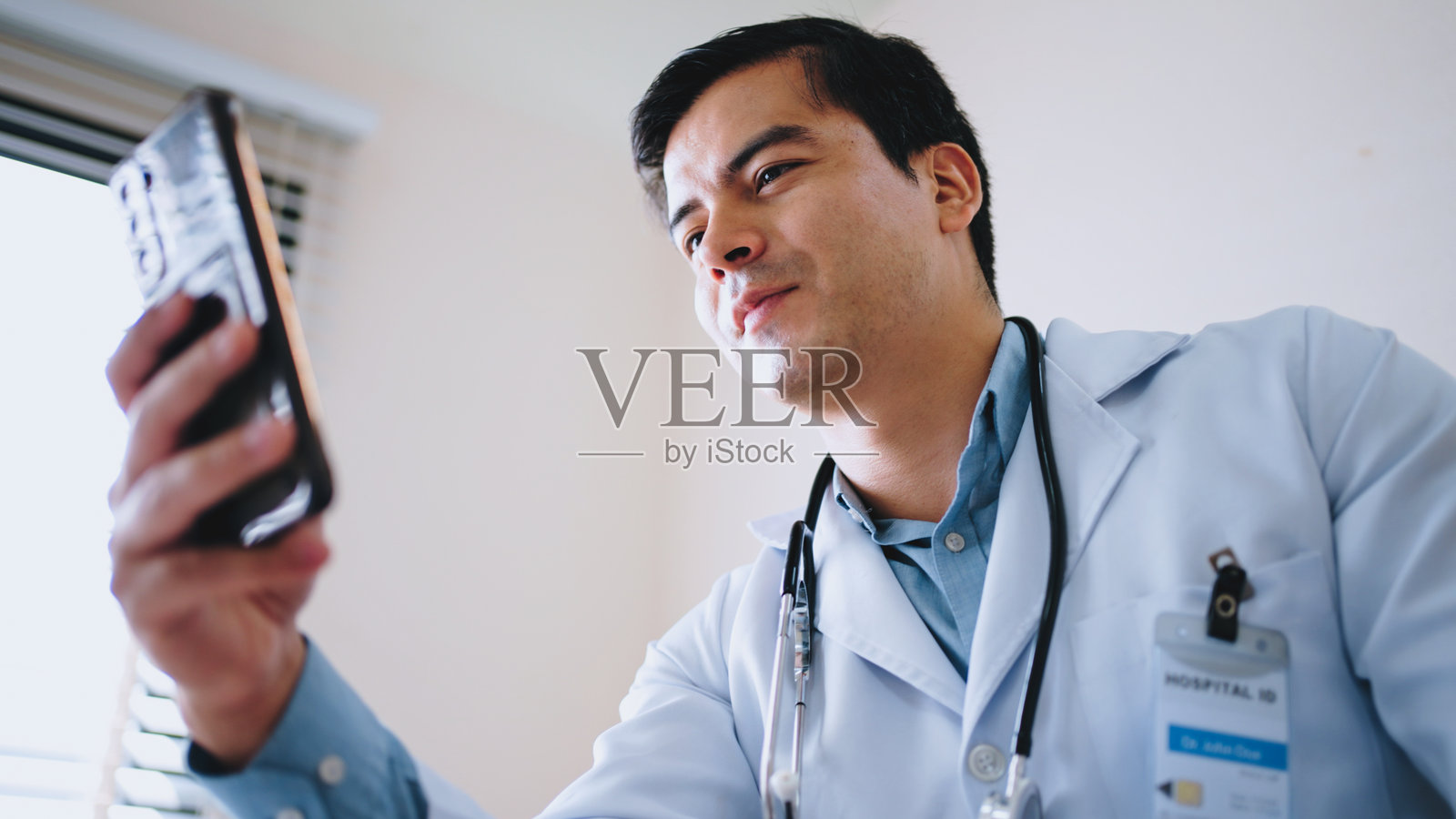 男医生在工作场所使用智能手机进行在线咨询照片摄影图片