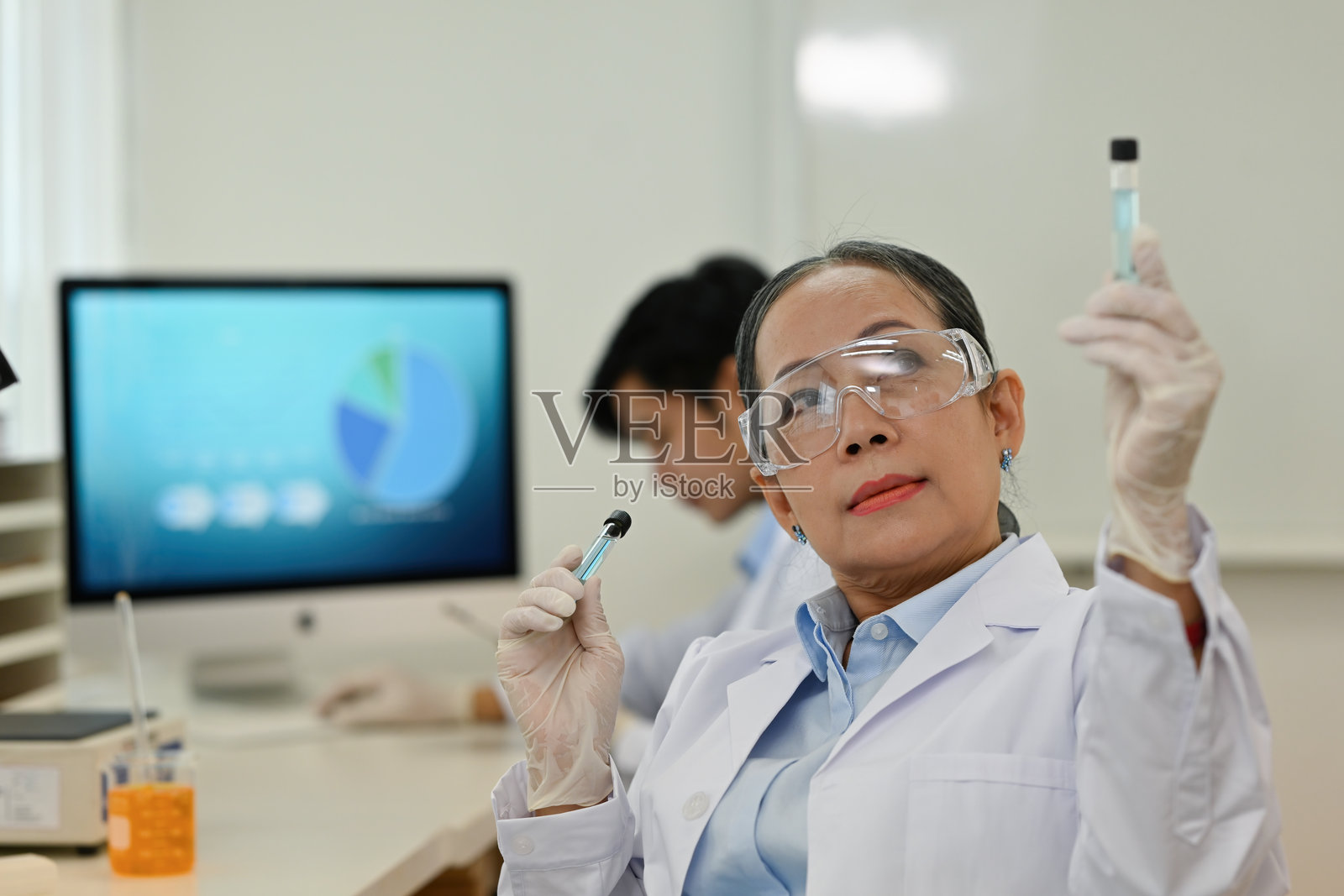 一位资深女医学或科学研究人员在实验室里观察试管中的物质照片摄影图片