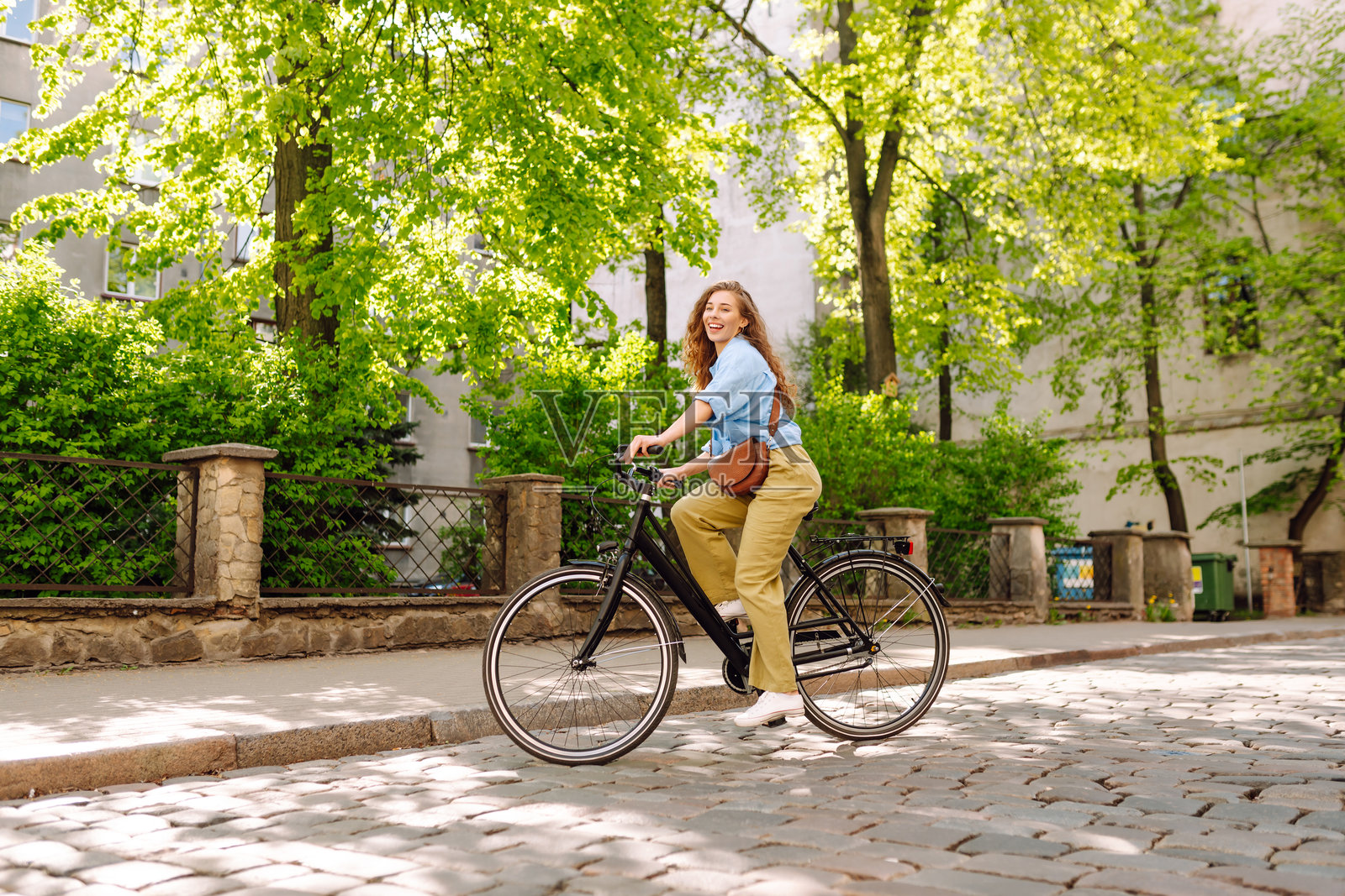 快乐的女人在城市街道上骑自行车。照片摄影图片