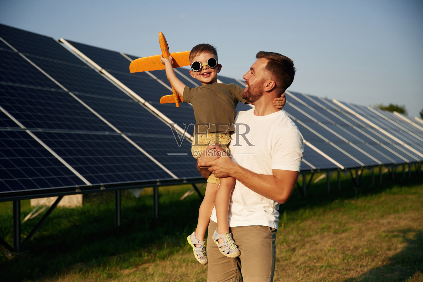 手中的玩具飞机：父亲和儿子在太阳能电池板旁照片摄影图片