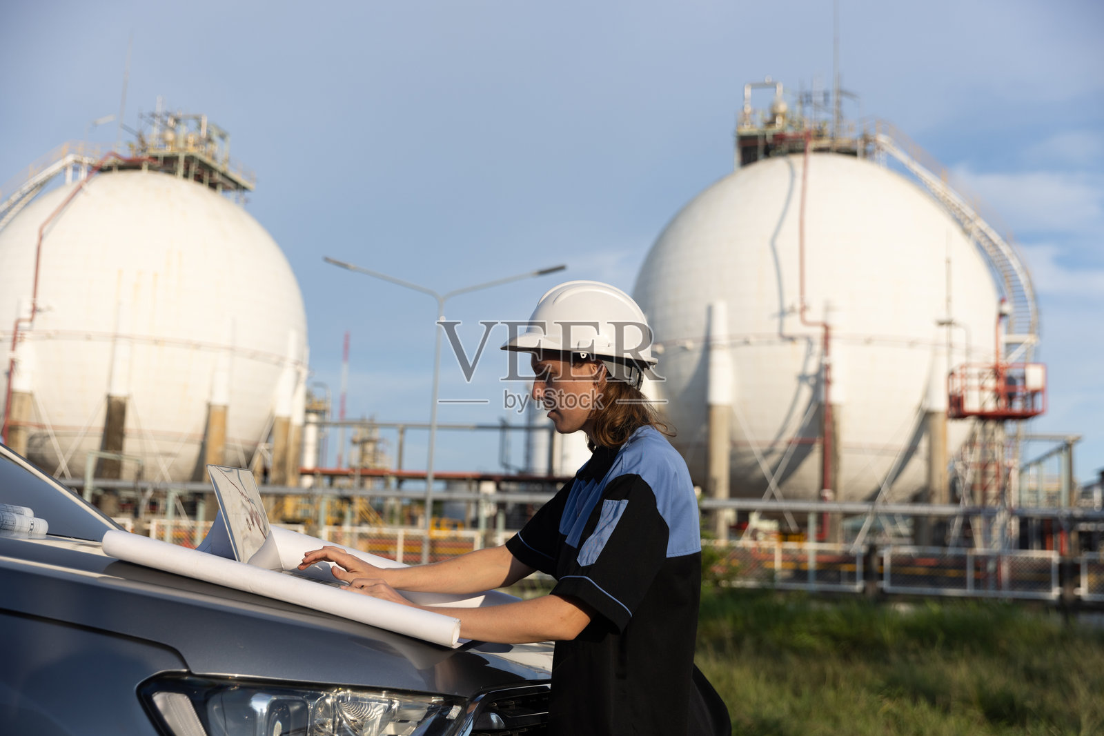 石化行业资深人士审查蓝图，检查储油设施汽车引擎盖上的油气质量照片摄影图片