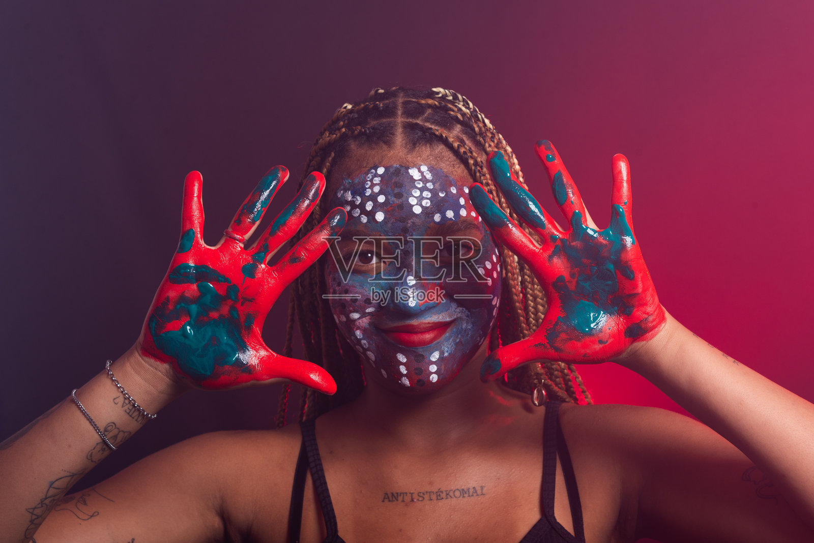 脸上涂着彩色油彩、扎着辫子的女人做着手势照片摄影图片