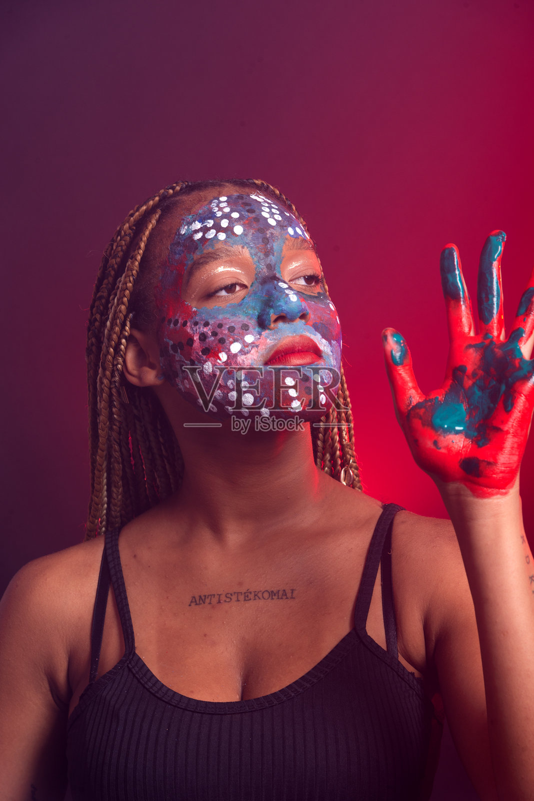 脸上涂着彩色油彩、扎着辫子的女人做着手势照片摄影图片