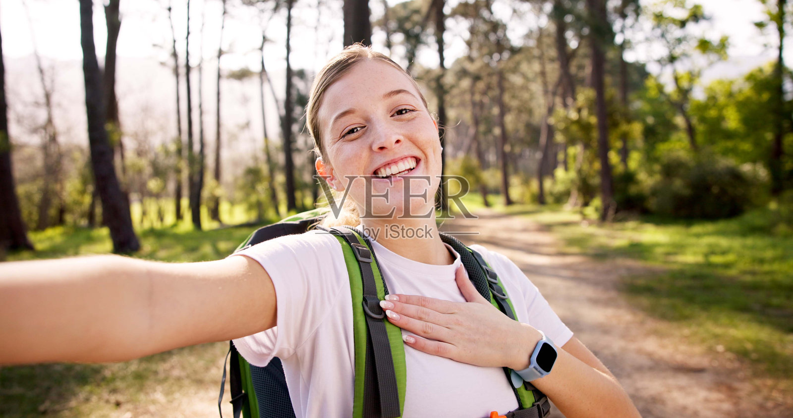 快乐的女性，背着登山包的肖像和自拍，记录旅行回忆或在森林中的直播冒险。女性，网红，微笑着背着包，进行徒步旅行的旅程，置身于树林或大自然中。照片摄影图片