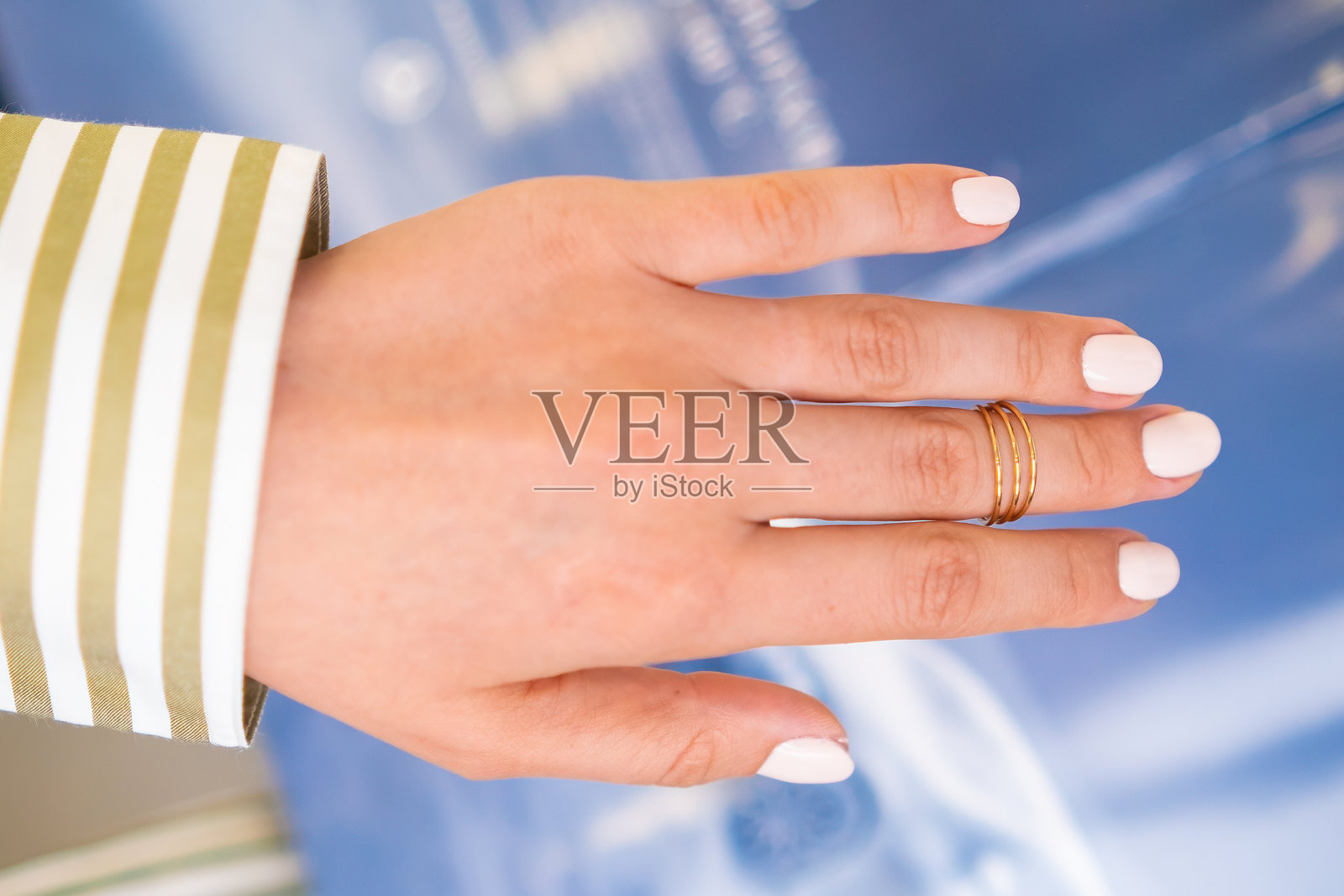 一只佩戴精致戒指的手展示了时尚的淡色凝胶指甲油美甲。照片摄影图片