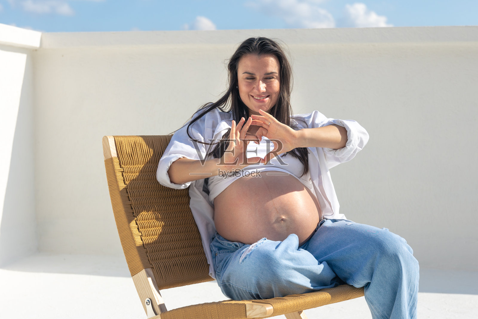 快乐的孕妇在天空背景下。怀孕的概念。照片摄影图片