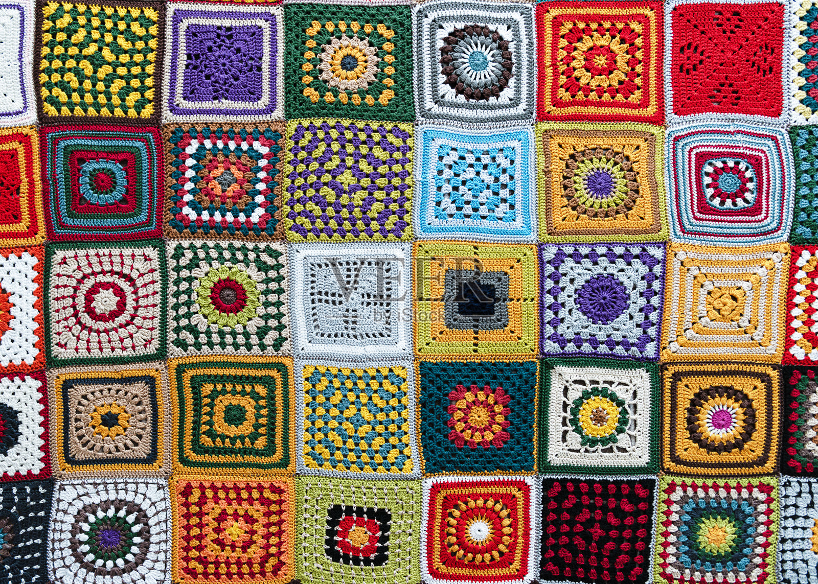 从上方俯瞰美丽的多彩格子毯，由不同图案的钩针奶奶方块制成。照片摄影图片