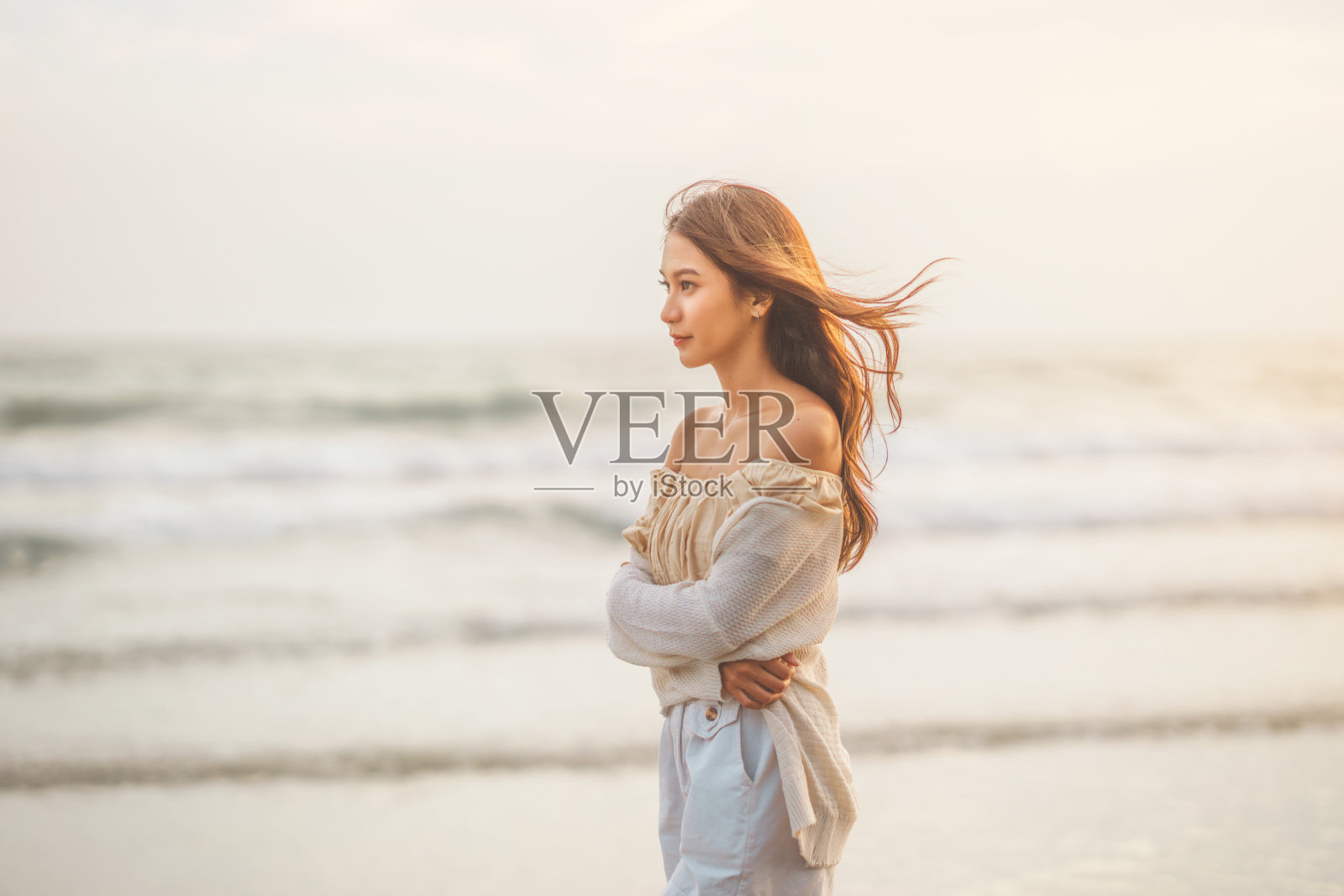 沮丧的亚洲年轻女人独自站在海滩上，双手交叉，孤独，心情不好，抑郁概念照片摄影图片