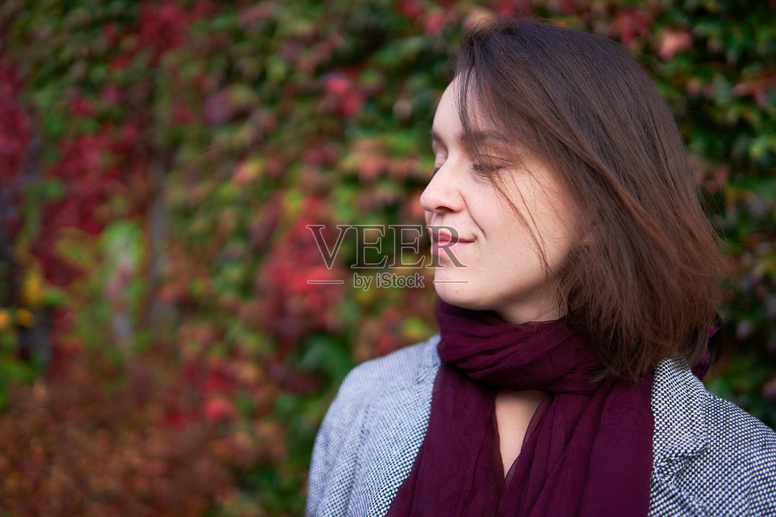 30岁中等身材的女性穿着红色薄棉布裙子，站在秋季花园中照片摄影图片