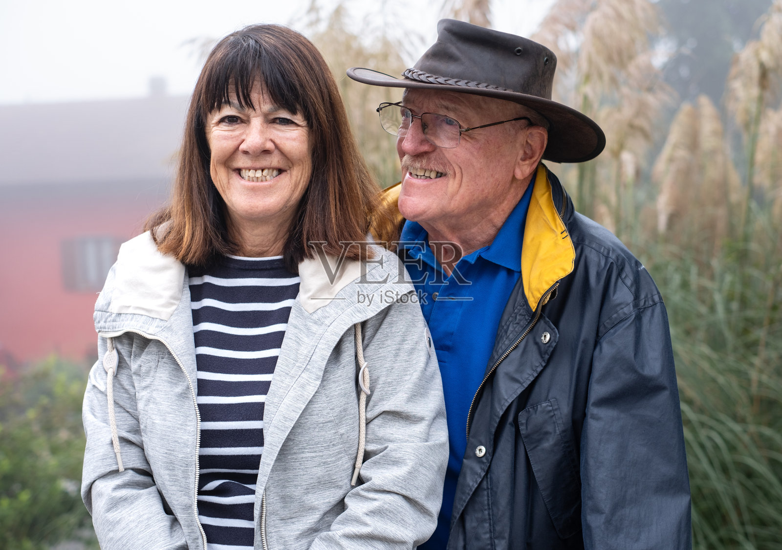 在雾霭弥漫的日子里，微笑的白人老年夫妇在户外亲密相伴，享受自然和健康的生活方式，度过退休或假期时光。照片摄影图片