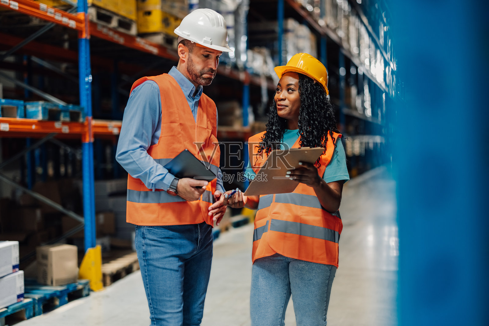 多种族工人在仓库中手持工具讨论物流。照片摄影图片