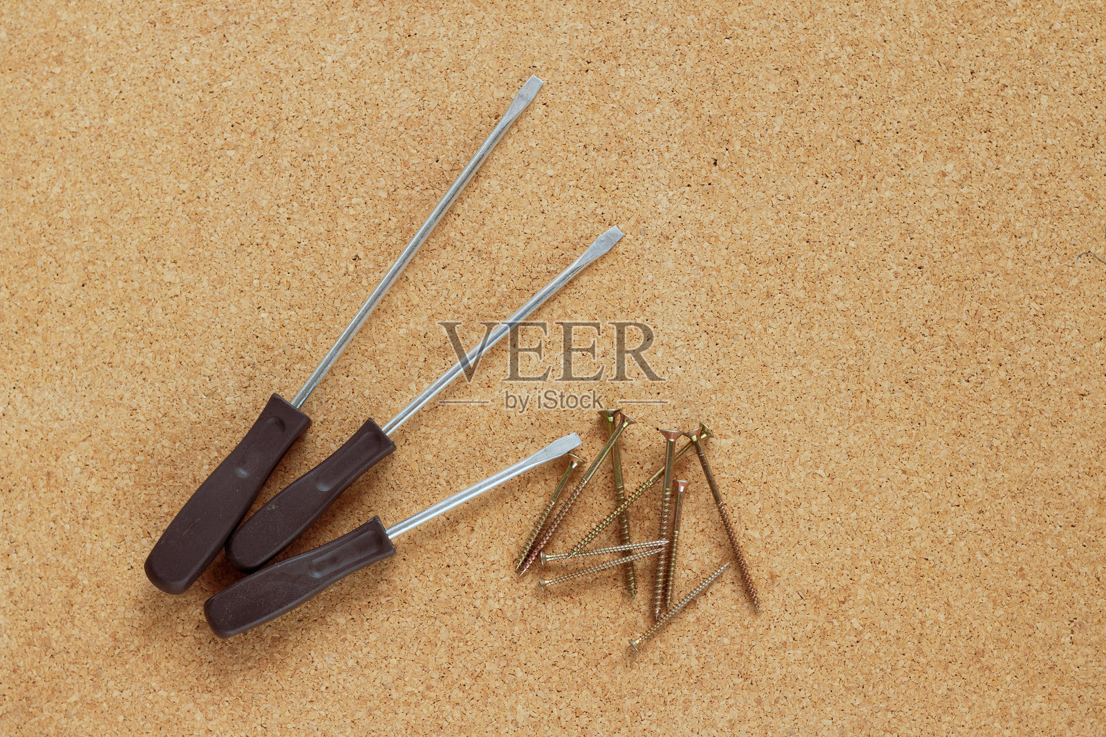 软木板上的螺丝刀和螺丝照片摄影图片