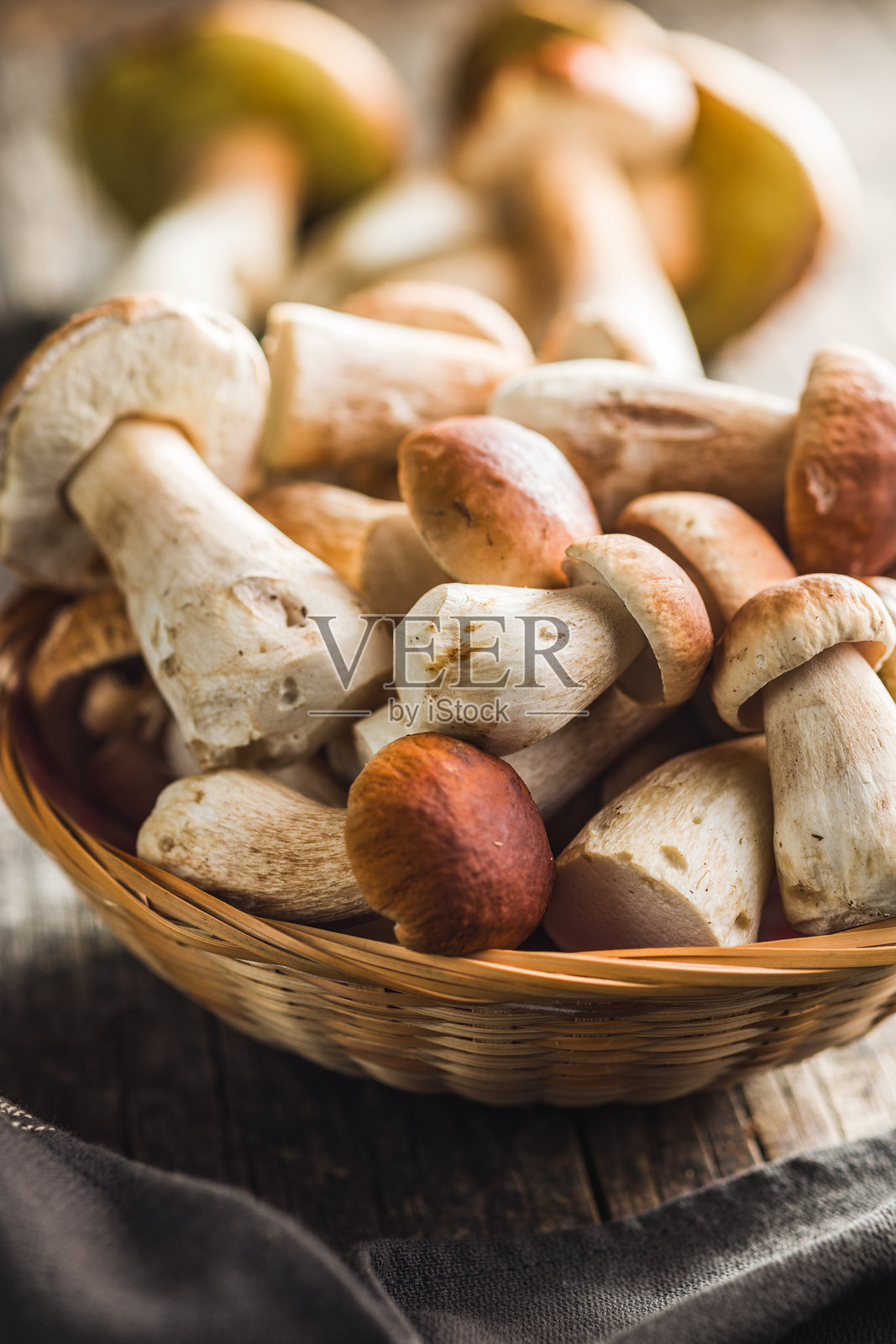 新鲜的牛肝菌放在木桌上的篮子里。照片摄影图片