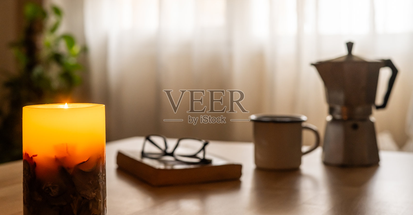 在窗边享受完美的早晨，咖啡机、冒着热气的咖啡或茶、一支摇曳的蜡烛和一本好书——这是放松和温馨时刻的理想环境。照片摄影图片