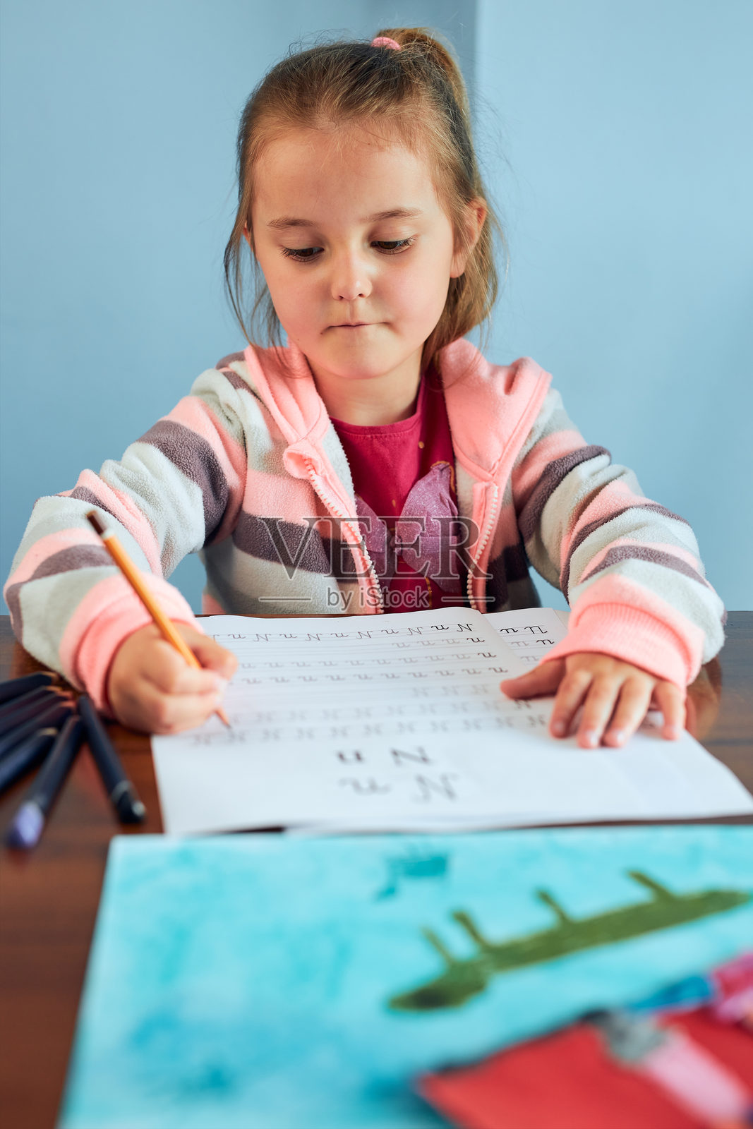 在家在桌子上写书的可爱女孩照片摄影图片
