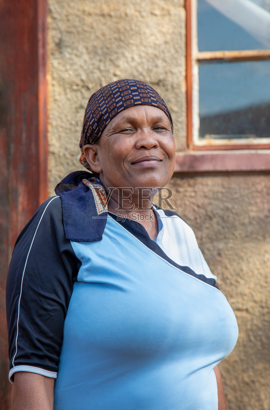 非洲村庄，单身非洲女性在她的房子前面披着围巾的肖像照片摄影图片
