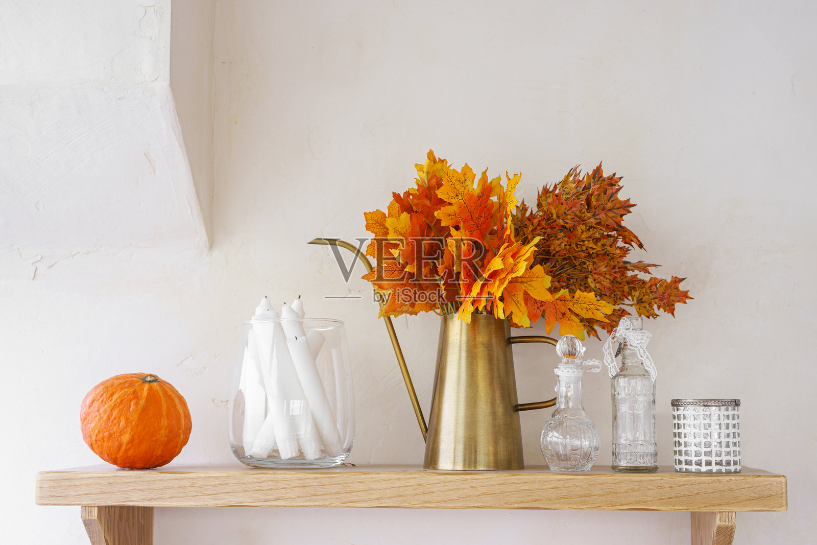 秋季装饰，鲜艳的树叶和南瓜摆放在白色灰泥墙背景上的木架上照片摄影图片