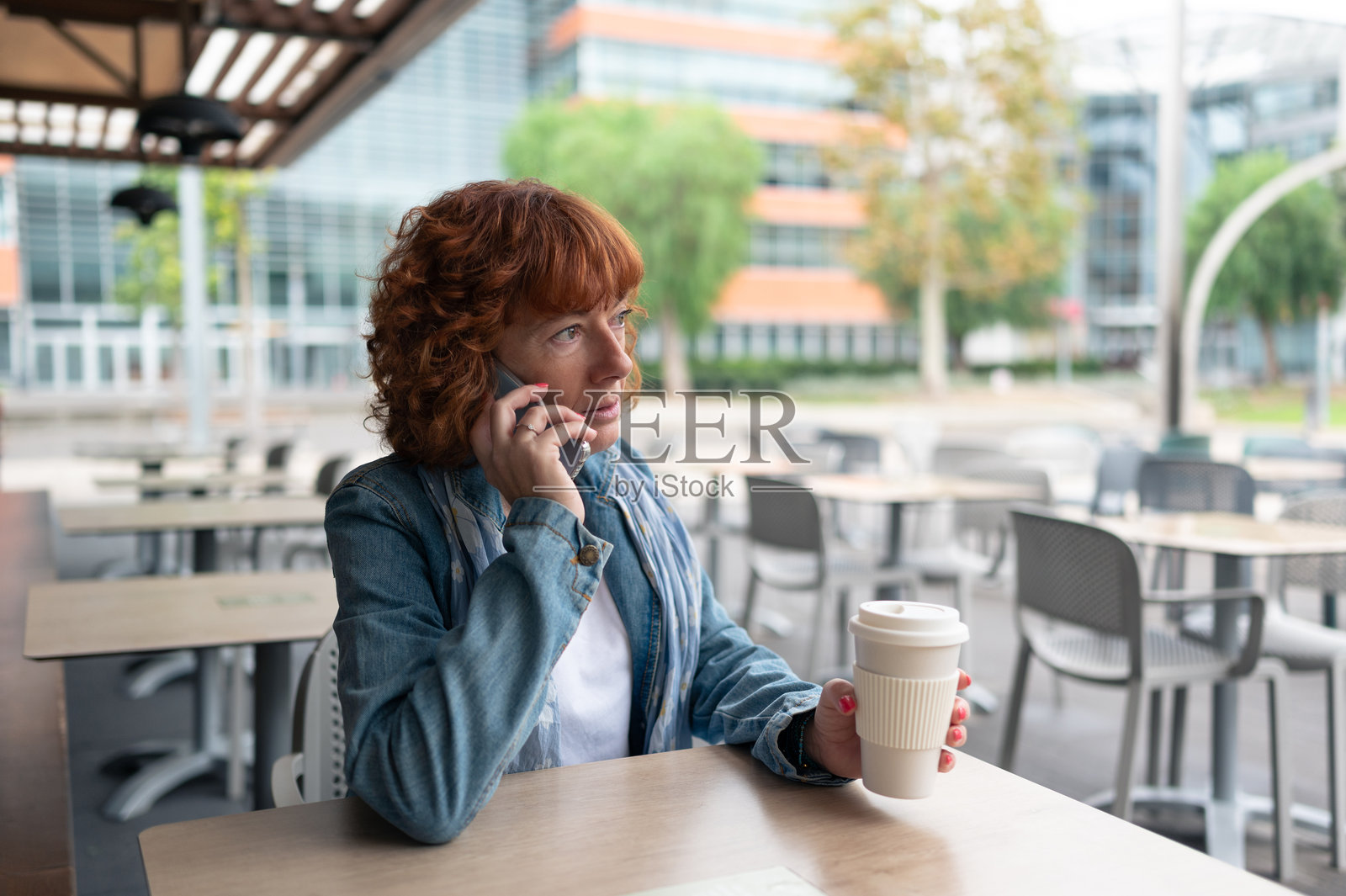 一位女性坐在咖啡馆的桌子旁，正在用手机通话。照片摄影图片