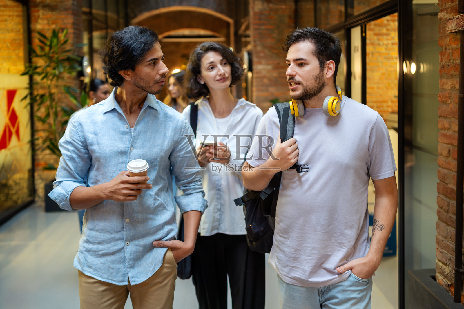 一群年轻的商务人士在办公室走廊里走动并交谈照片摄影图片