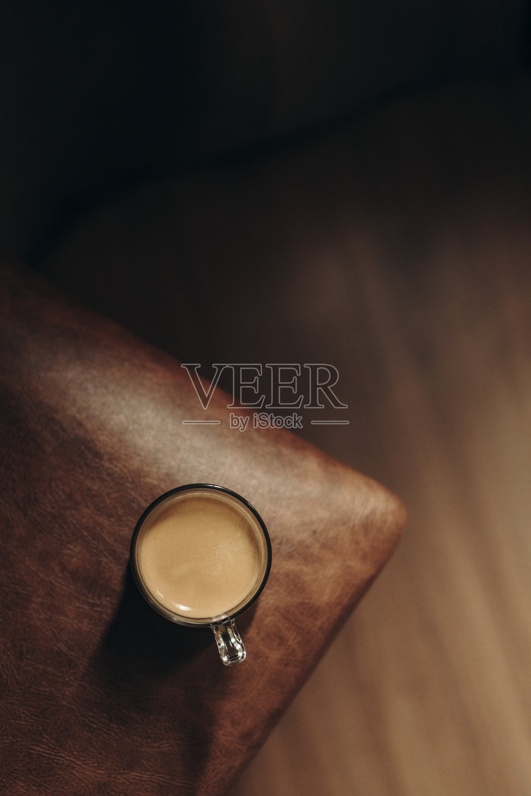 咖啡杯的俯视图，背景为棕色皮革和木材。照片摄影图片