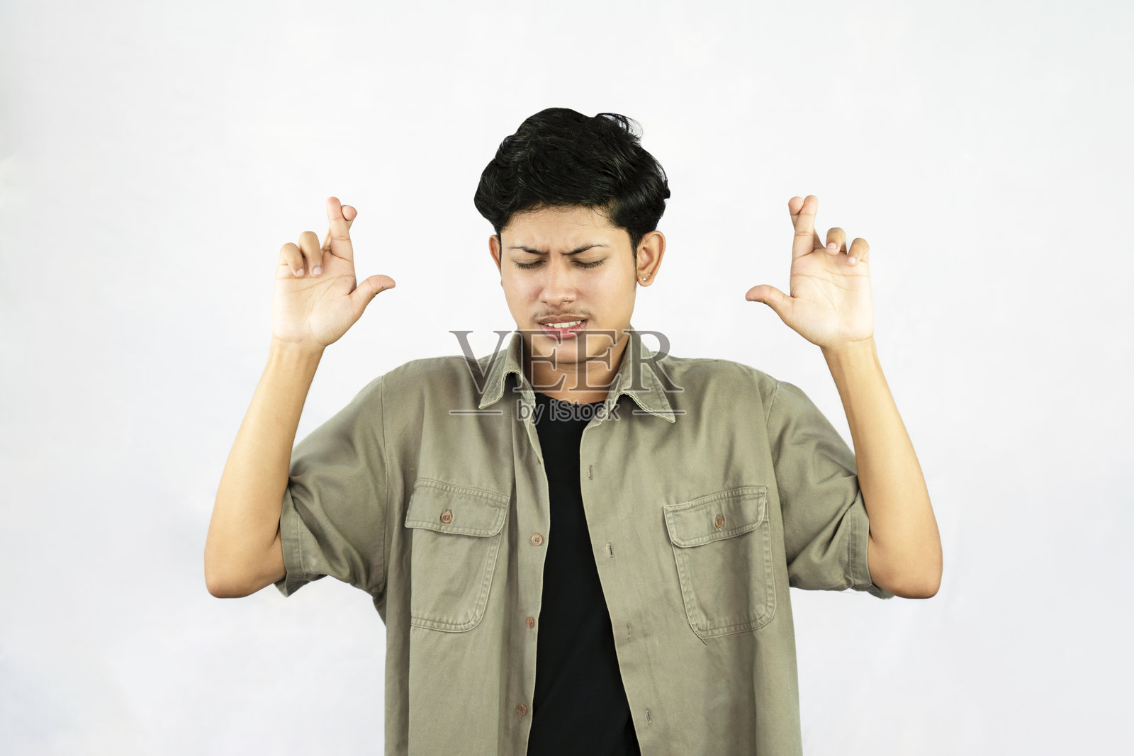 交叉手指，思考和悲伤表情的忧虑的英俊年轻男子照片摄影图片