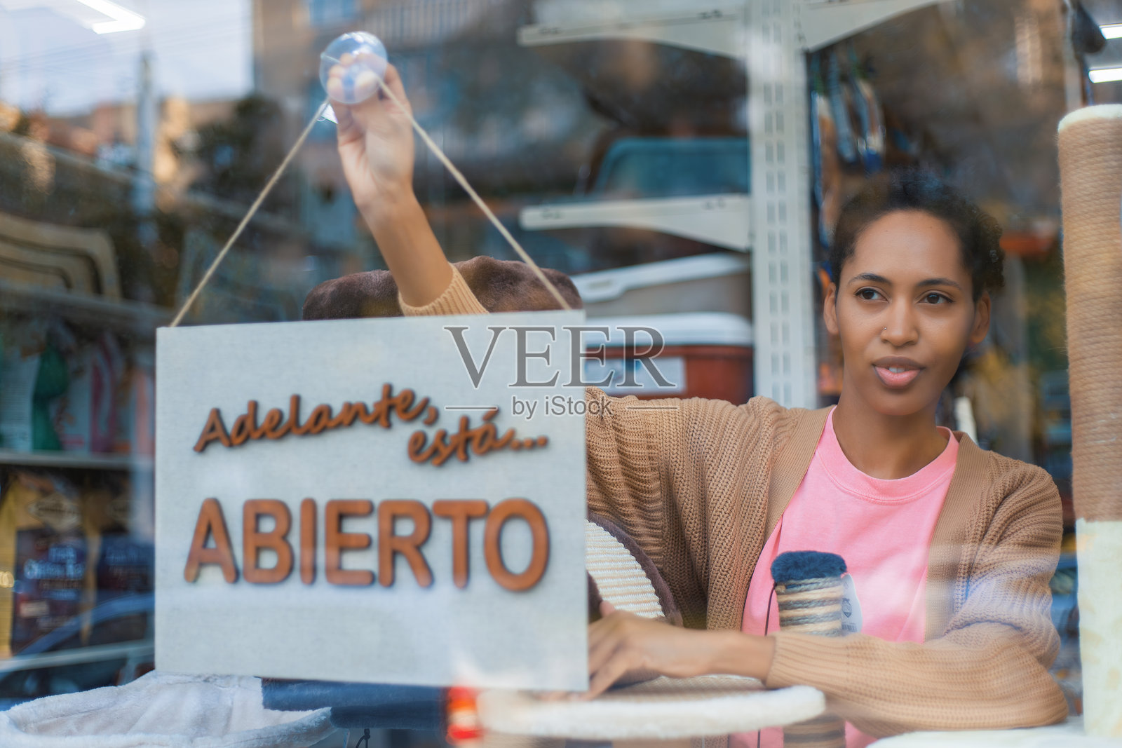 商店员工在宠物店的玻璃门上贴上开放标志。照片摄影图片