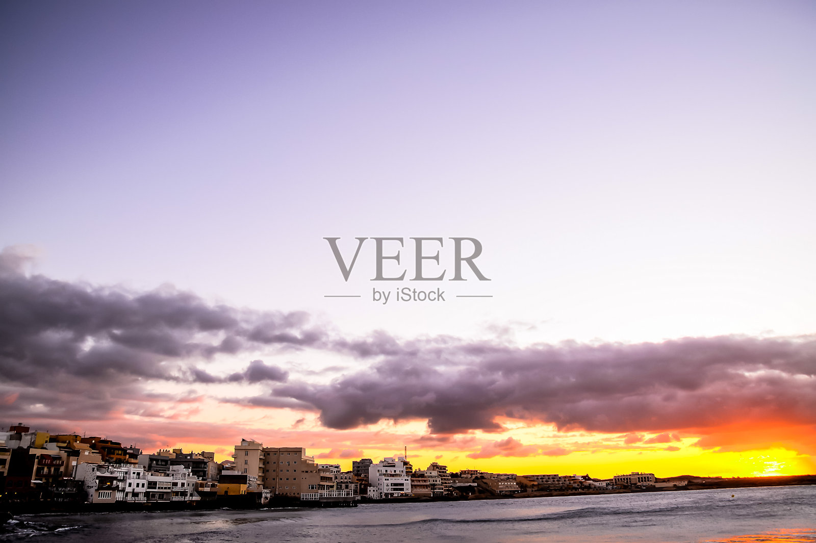 城市上空美丽的日落，背景是一片辽阔的水域照片摄影图片