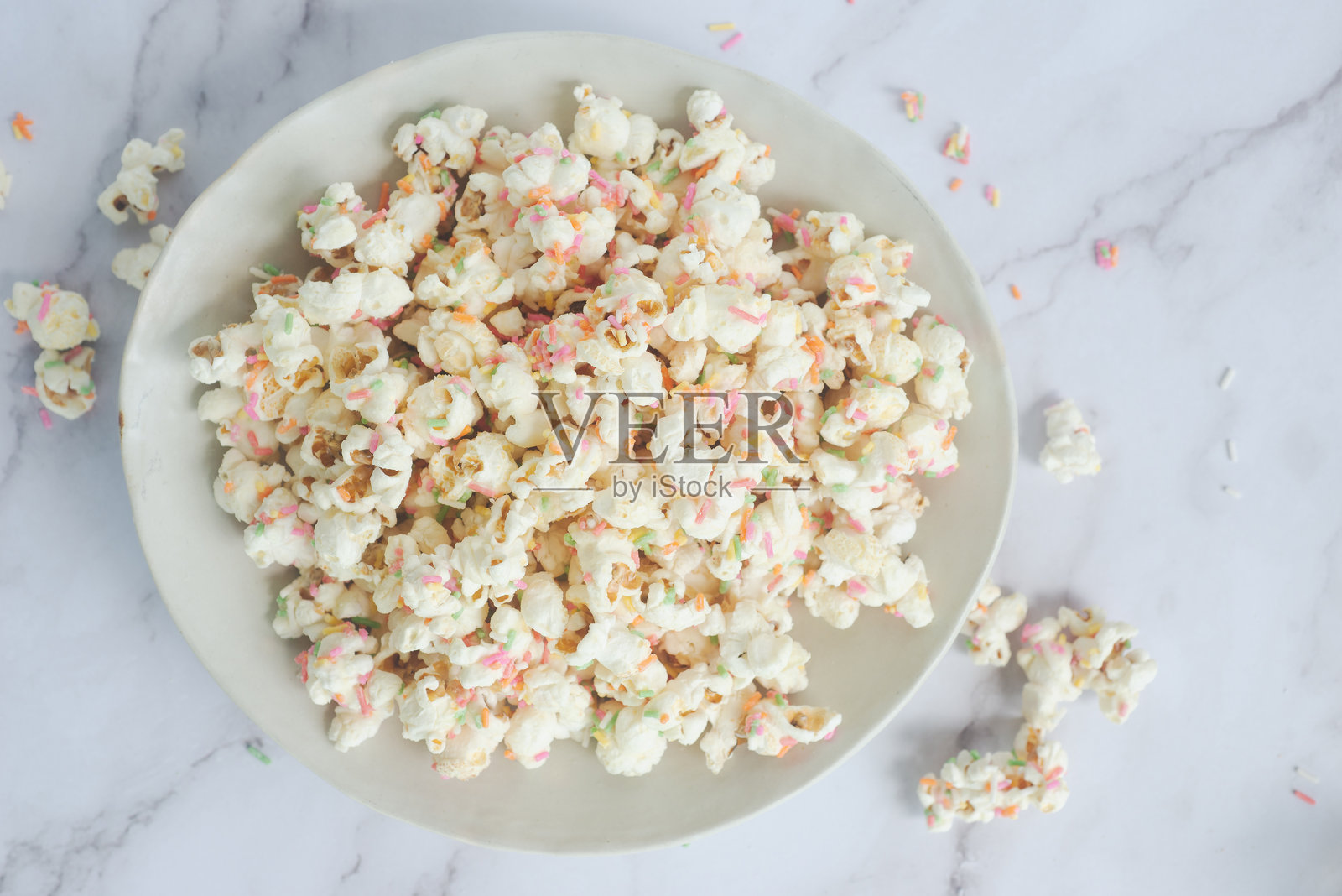 白巧克力五彩纸屑爆米花在陶瓷碗中。照片摄影图片