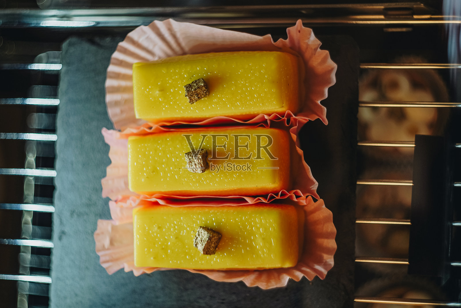 黄色美丽的奶酪甜点放在黑色盘子上出售，俯视图。面包店内展示的各种欧洲糕点。照片摄影图片