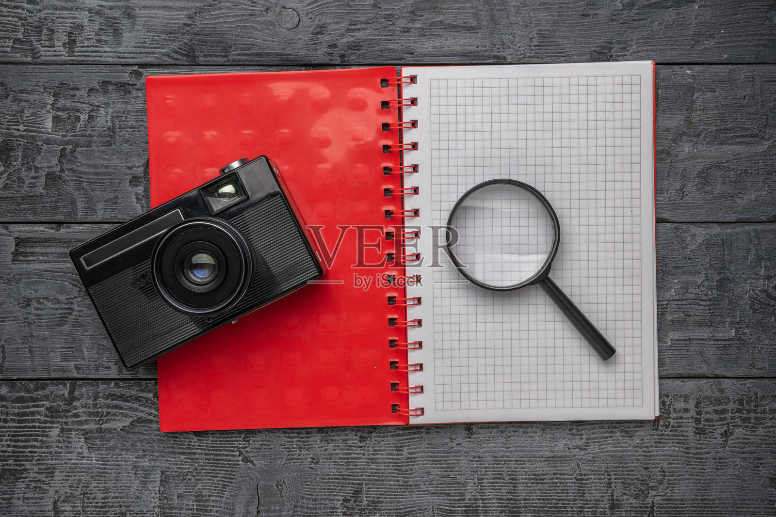 复古相机和放大镜放在打开的笔记本上，背景是木质的。照片摄影图片