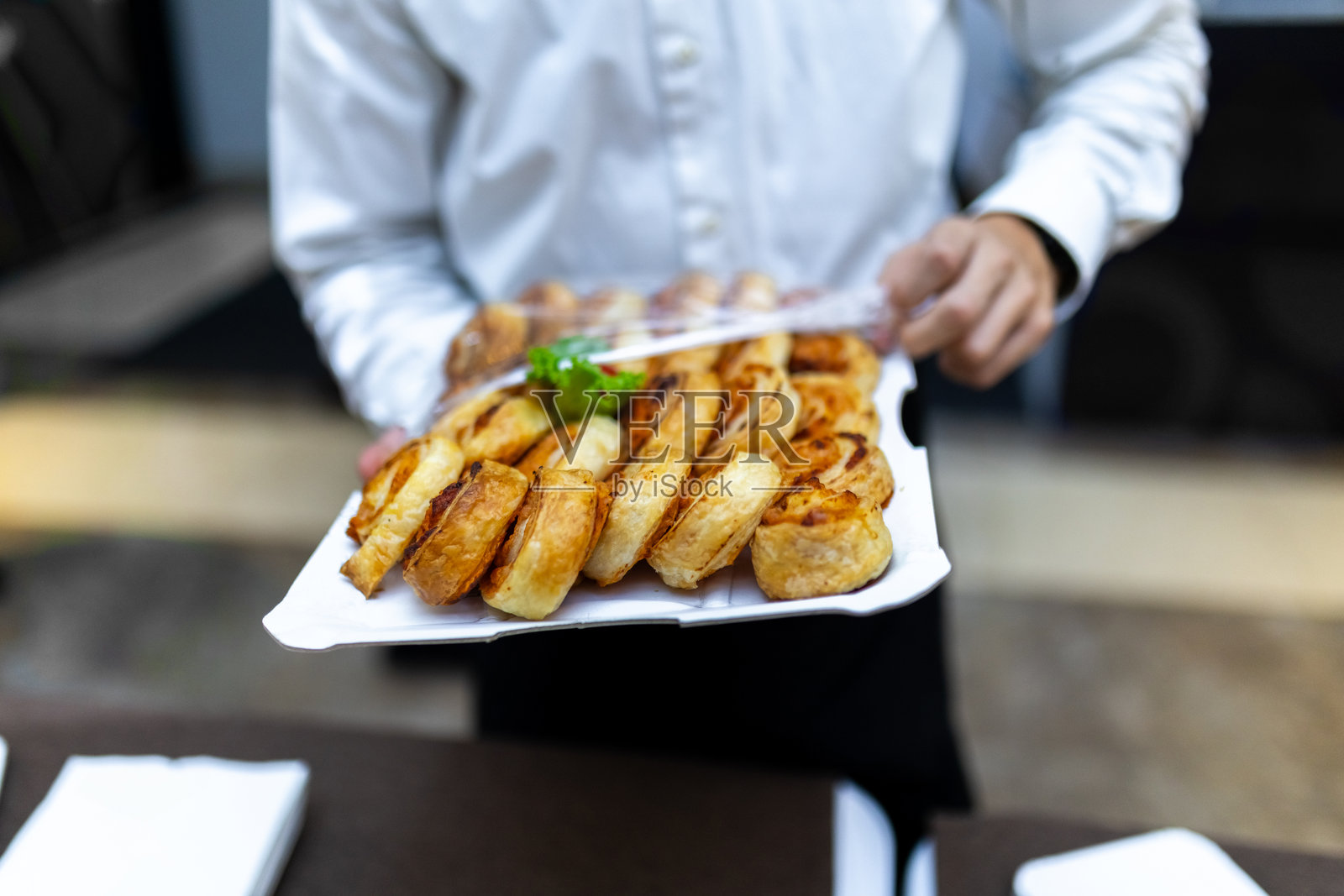 一名服务员在现代餐饮环境中为下午的宴会活动提供新鲜出炉的糕点照片摄影图片