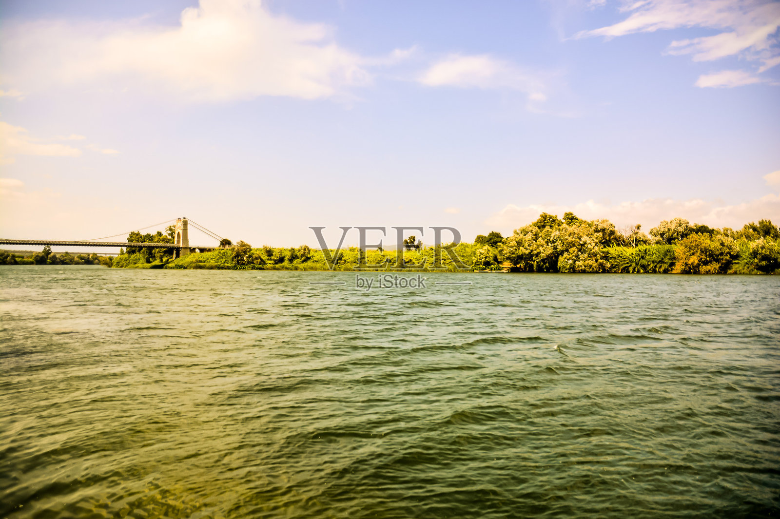 一座桥横跨一条河流，另一边是一片绿色的森林。照片摄影图片