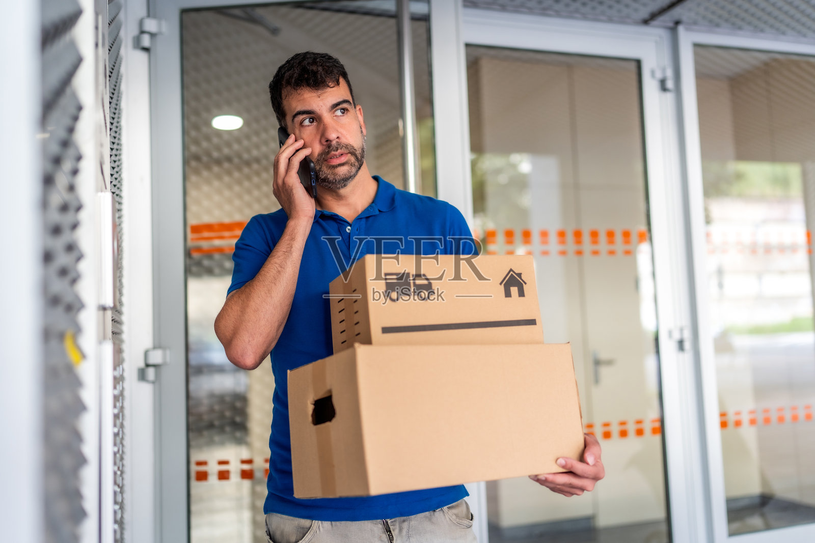 送货员在房子外面与手机通话照片摄影图片