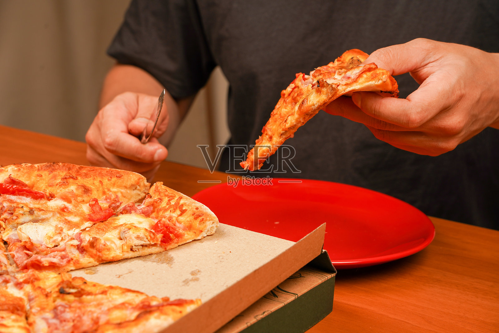 油腻食物。手拿比萨饼的一片，特写视角。比萨店的美味食物。外卖概念。快餐订单。餐厅广告。美味的奶酪比萨。比萨。 不健康的食物。垃圾食品。照片摄影图片