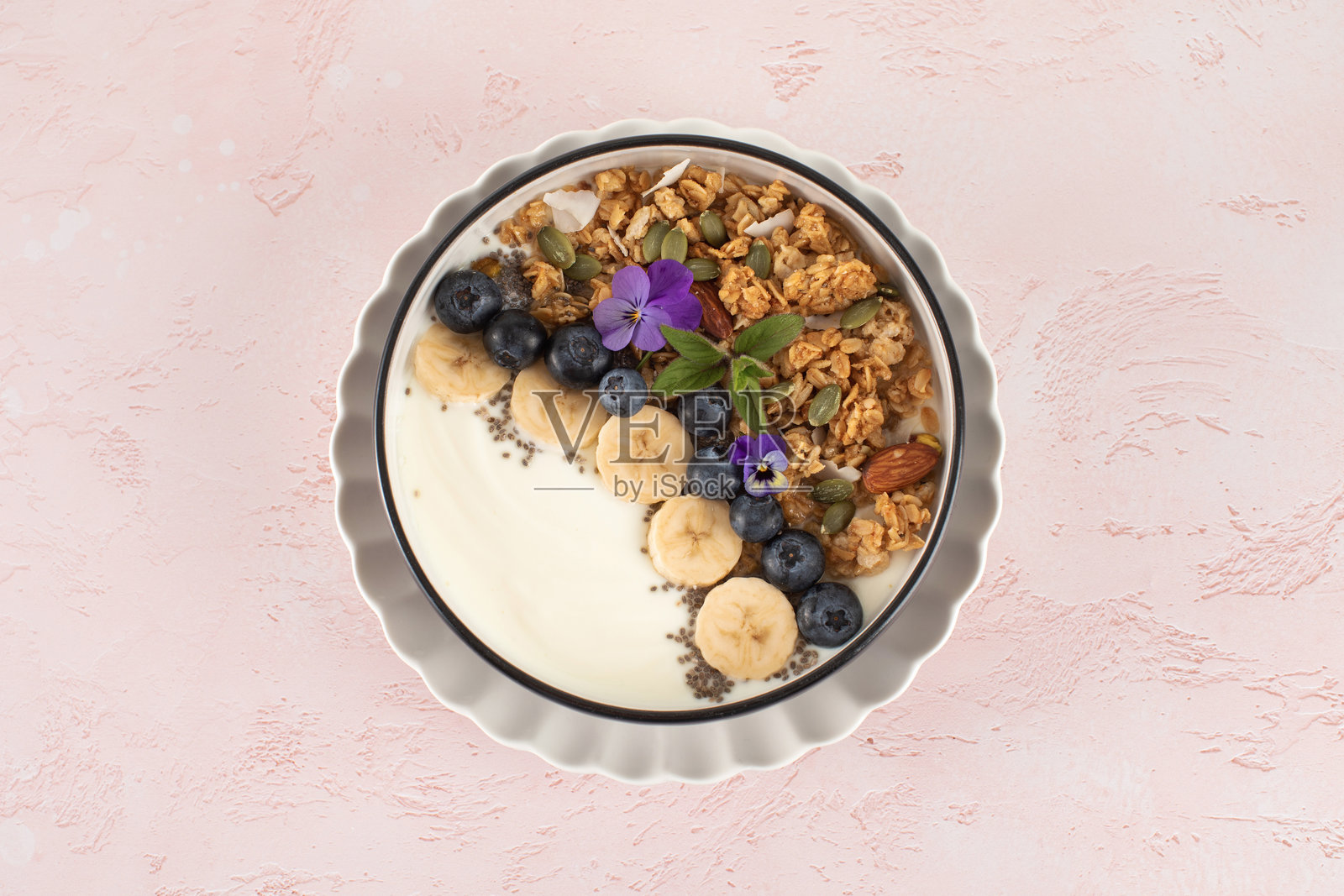 健康营养的早餐：天然希腊酸奶、格兰诺拉麦片和新鲜浆果，背景为粉色。照片摄影图片