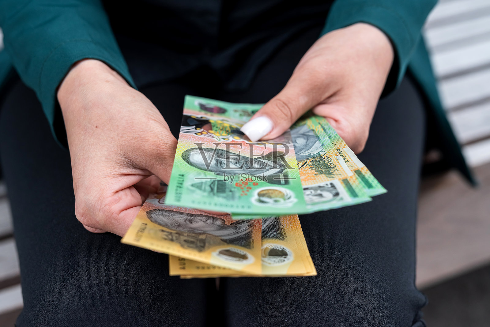 女性在城市街道上数着50和100澳元的货币。澳元储蓄概念照片摄影图片