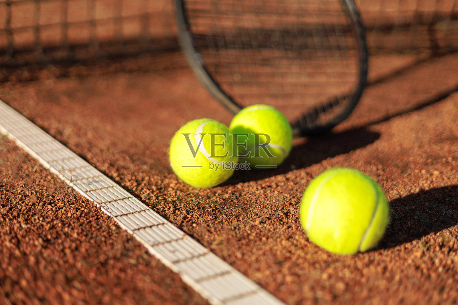 户外夏季阳光明媚的网球场上，网球与火箭靠近网的特写镜头照片摄影图片