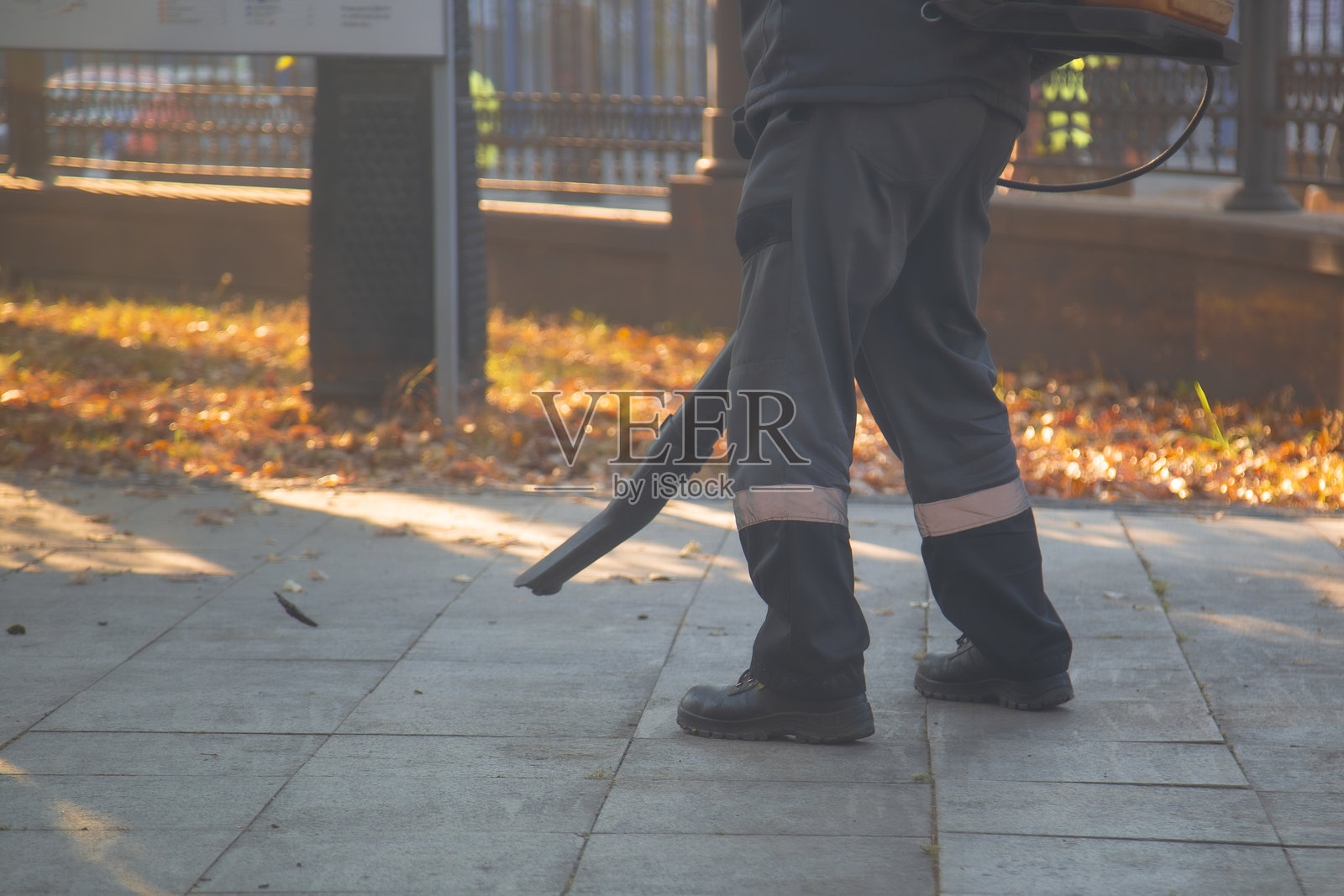 一名公用事业工人正在用特殊设备清理路上的落叶。照片摄影图片
