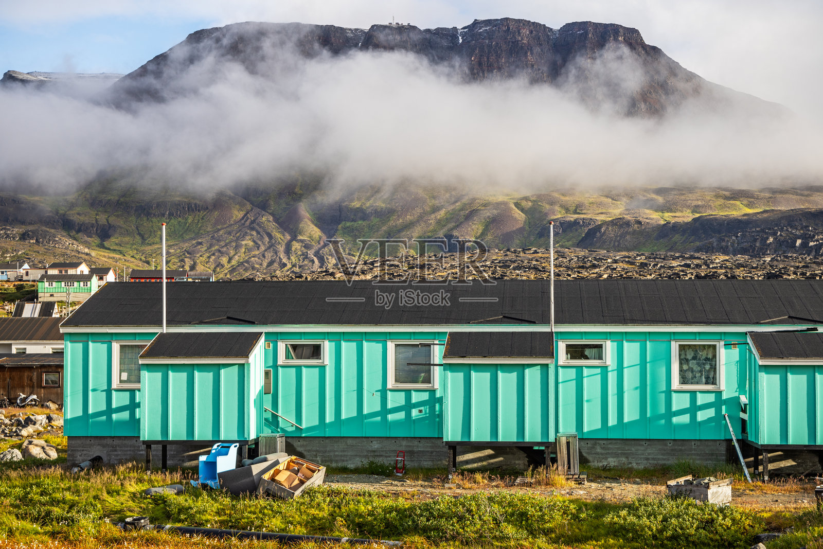 现代北极住宅建筑位于山脉前方，云雾缭绕。照片摄影图片