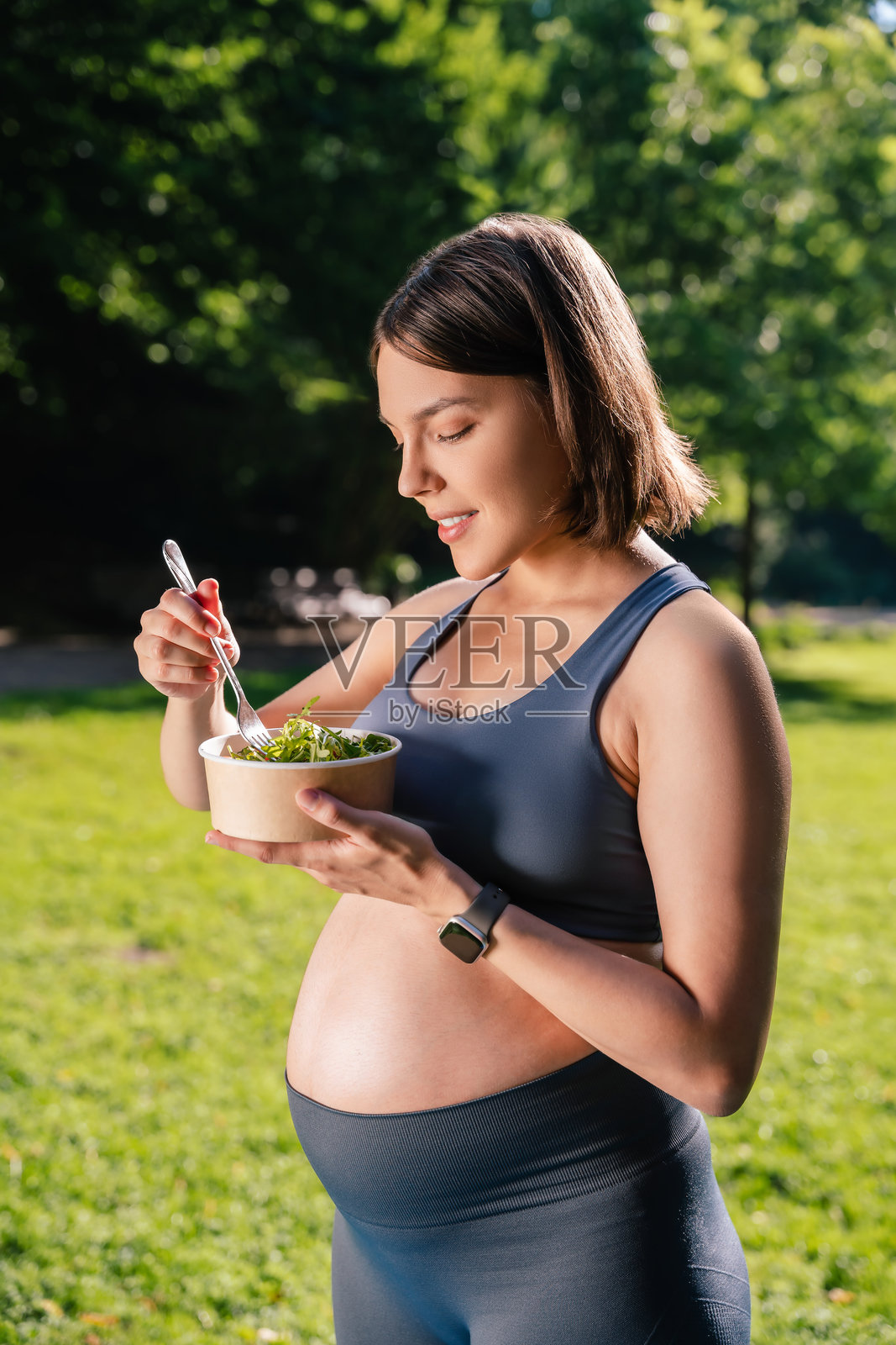 女性在公园享受健身，吃富含维生素的健康餐，关注孕期的健康与幸福。照片摄影图片