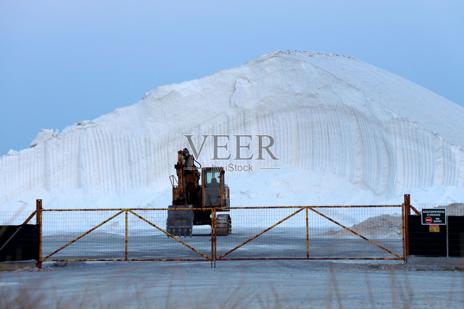 盐矿中的挖掘机和盐堆。照片摄影图片