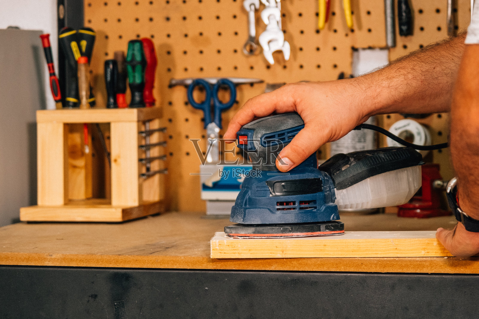 一个人正在使用电动砂光机打磨。照片摄影图片