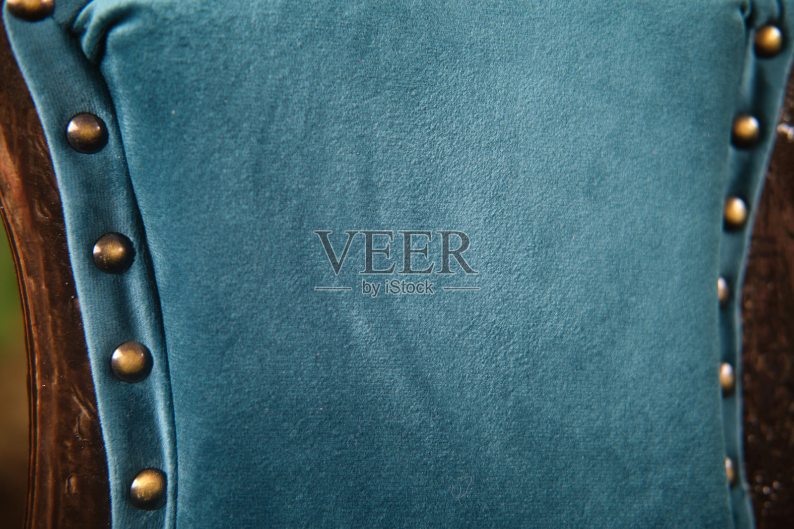 青绿色天鹅绒 upholstery 的特写，配有黄铜钉头装饰。用于家具设计和室内装饰的纹理面料的宏观拍摄。照片摄影图片