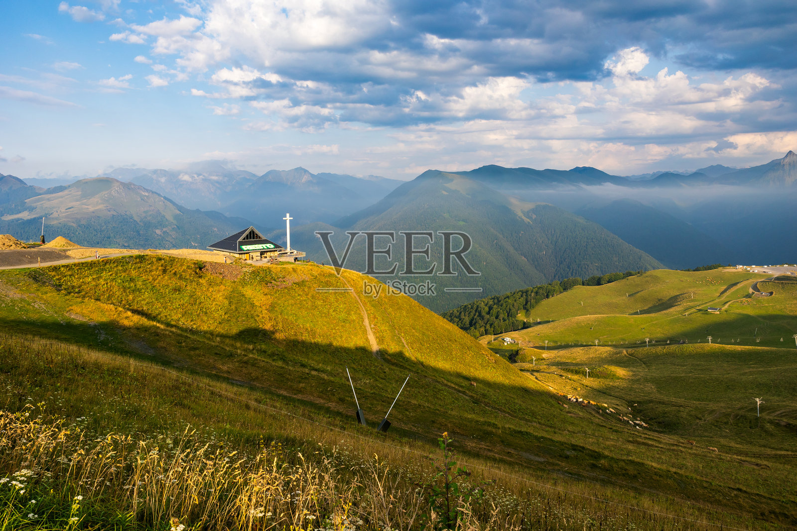 前教堂改建的餐厅，位于卢雄-超级巴涅尔滑雪胜地，俯瞰巴涅尔-德-卢雄镇及周围山脉，夏季景色。照片摄影图片
