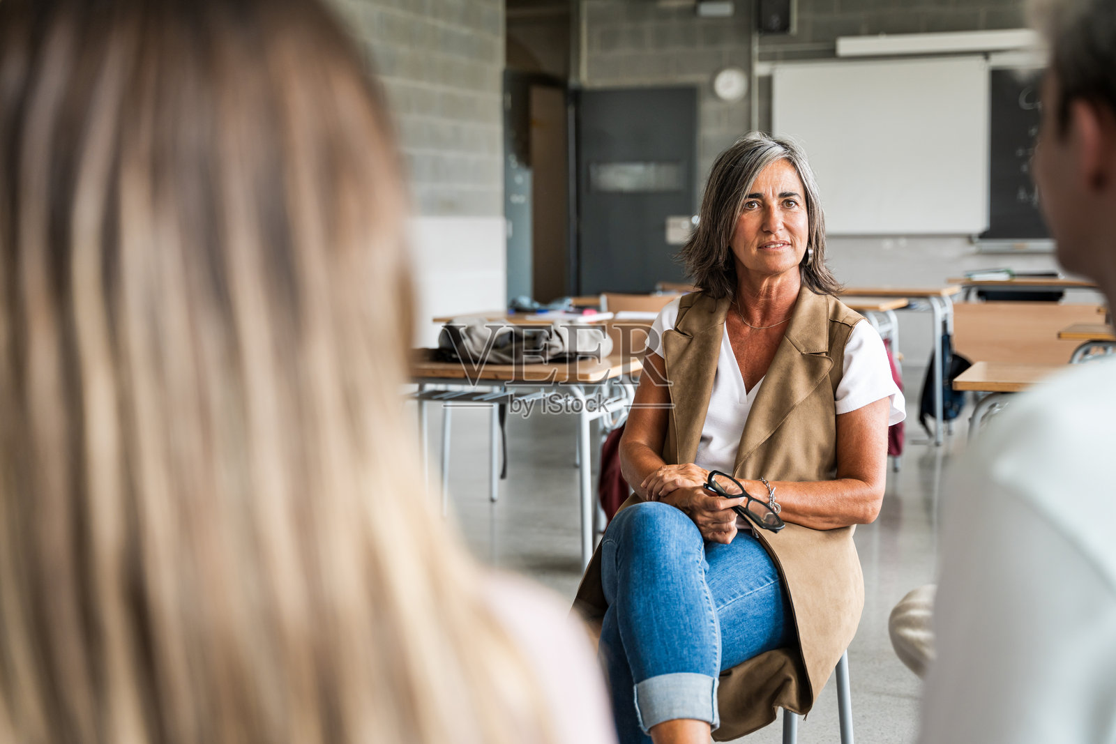 高中辅导员与一群学生交谈，提供指导和支持。教师在一旁倾听，表现出同理心。照片摄影图片