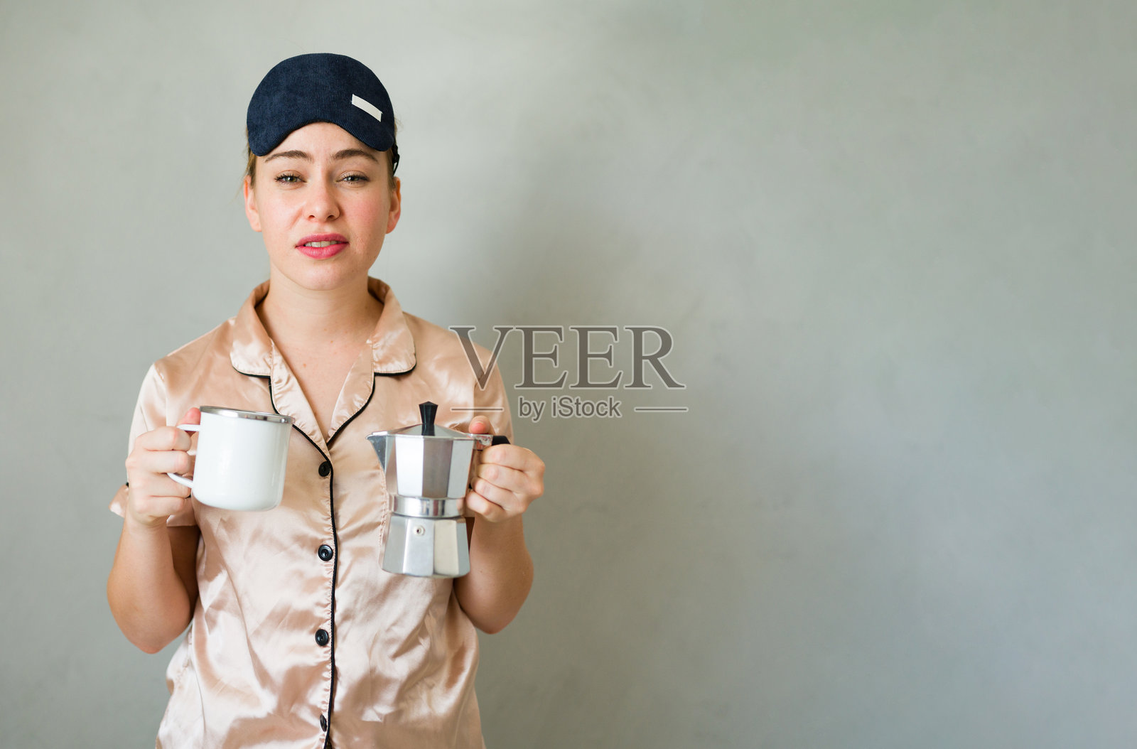 疲惫的女性穿着睡衣和睡眠面罩，早晨真的需要第一杯咖啡。照片摄影图片