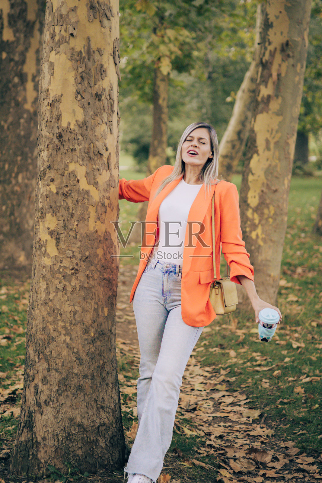 通勤时冥想。美丽的女商人在公园里穿着商务服装，享受工作后回家路上的宁静冥想时光。城市公园的咖啡休息时间，运用减压技巧。照片摄影图片